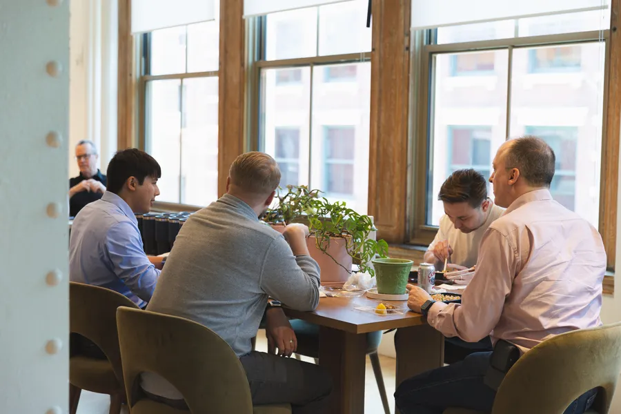 Team members having lunch together by the window